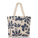 A canvas tote bag featuring a navy blue floral print over a warm beige and orange gingham check pattern, with cream-colored shoulder straps and a small leather brand patch on the front.