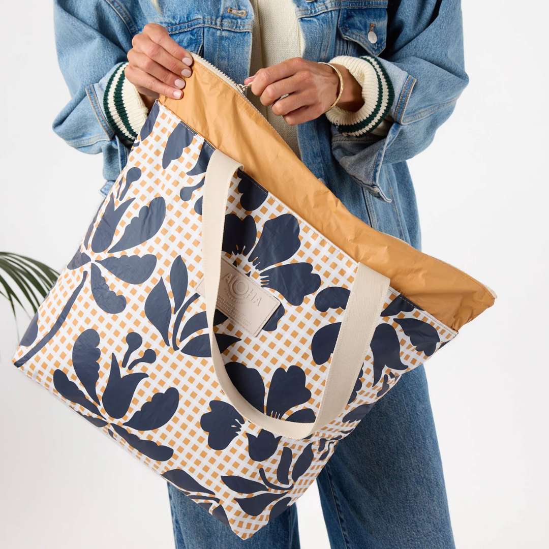 Person holding a floral-patterned tote bag with a white background