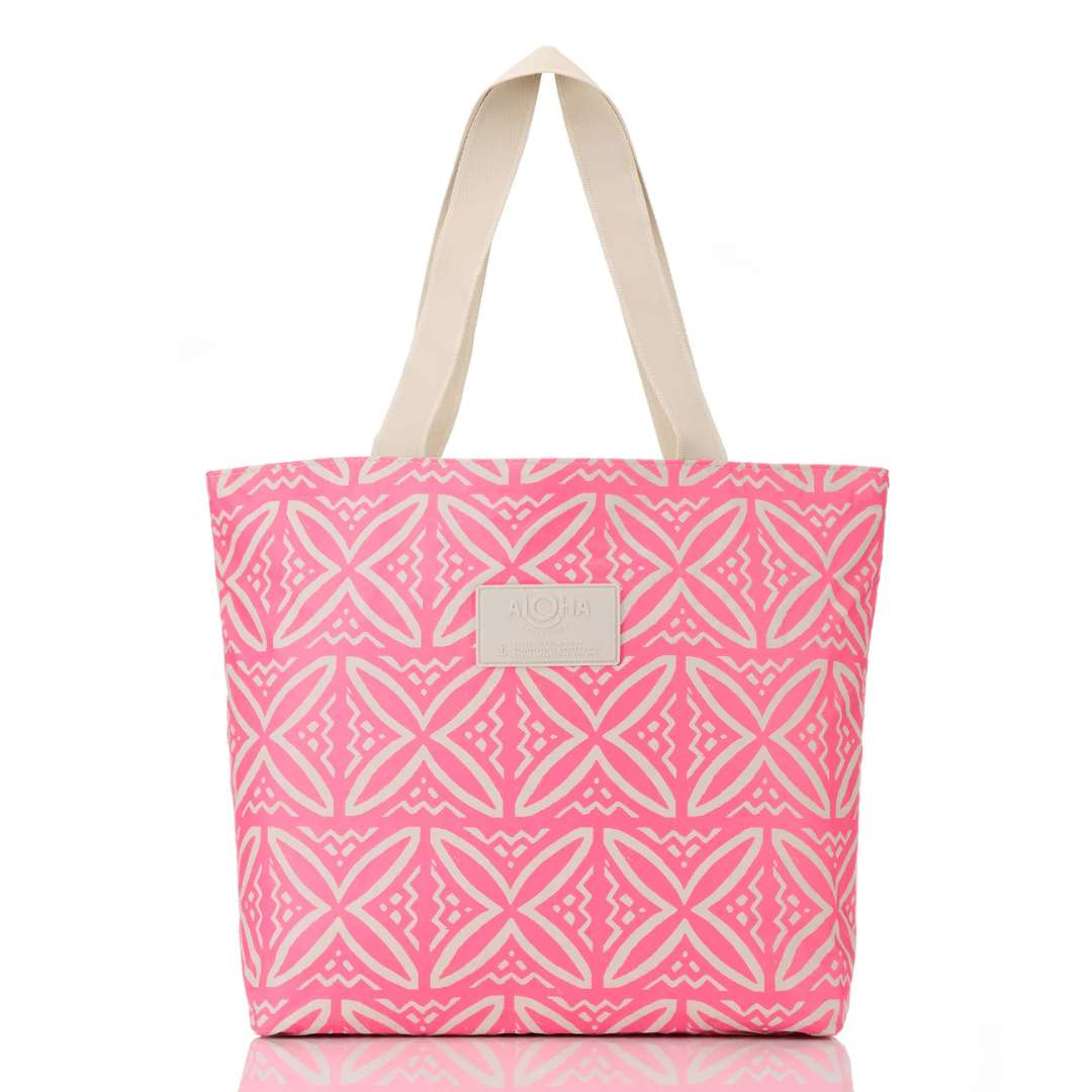 A pink tote bag with a white geometric pattern and beige shoulder straps, featuring a small beige brand patch on the front.