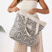 Person holding a patterned tote bag with a plain white background