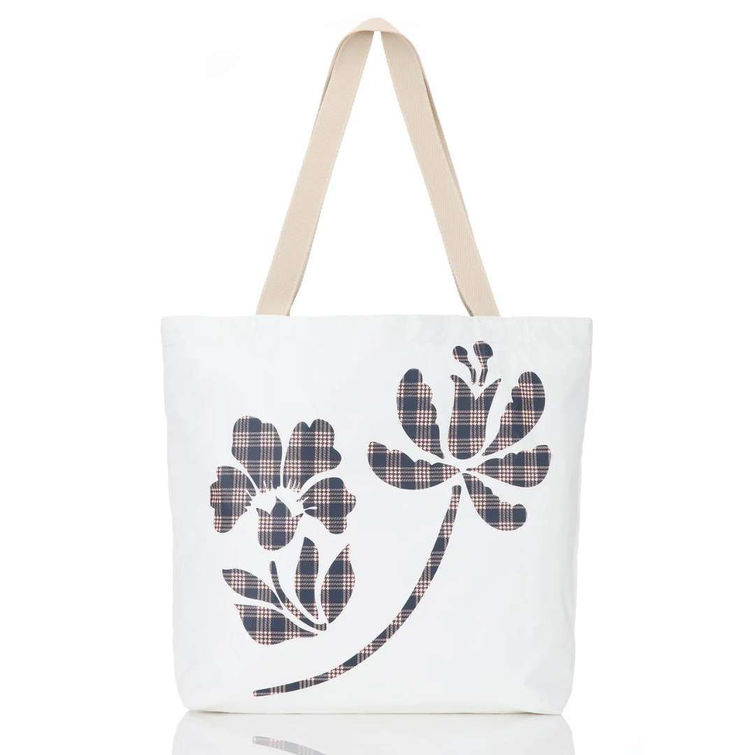 A white canvas tote bag with beige shoulder straps, featuring a stylized floral graphic on the front filled with a dark plaid pattern.