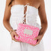 Person holding a pink and white patterned pouch with 'Aloha' branding.