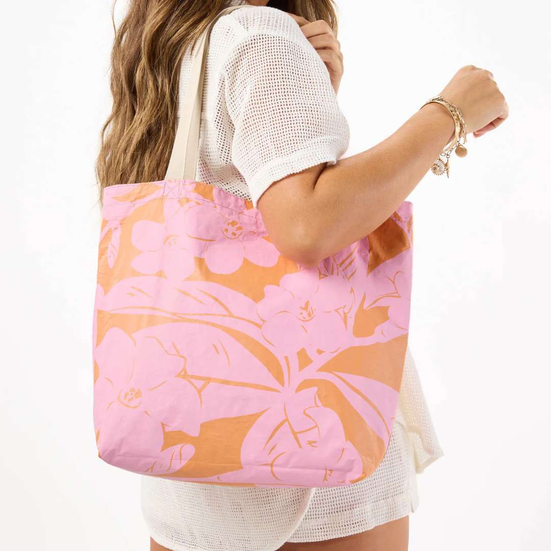 Woman holding a pink and orange floral tote bag on a white background