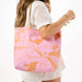 Woman holding a pink and orange floral tote bag on a white background