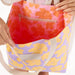 person holding a purple and orange bag open to show the different pink and orange inside print