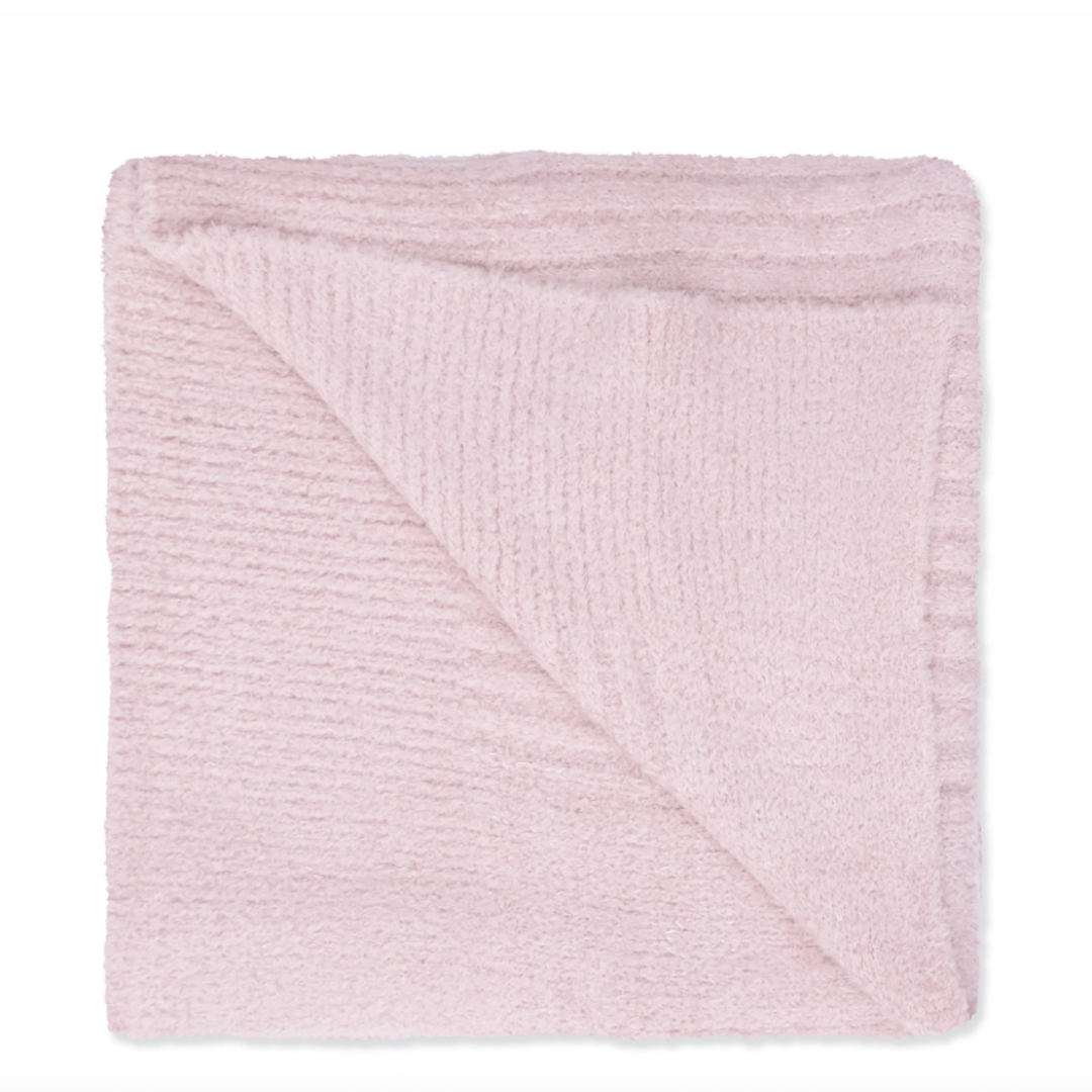 A folded light pink textured knit blanket with ribbed edges, shown on a plain white background.