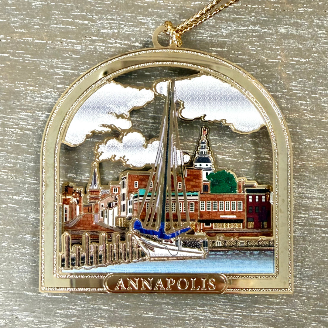 An arched enamel pendant necklace featuring a miniature Annapolis, Massachusetts cityscape with a sailboat, set in a gold-tone frame with a matching chain.