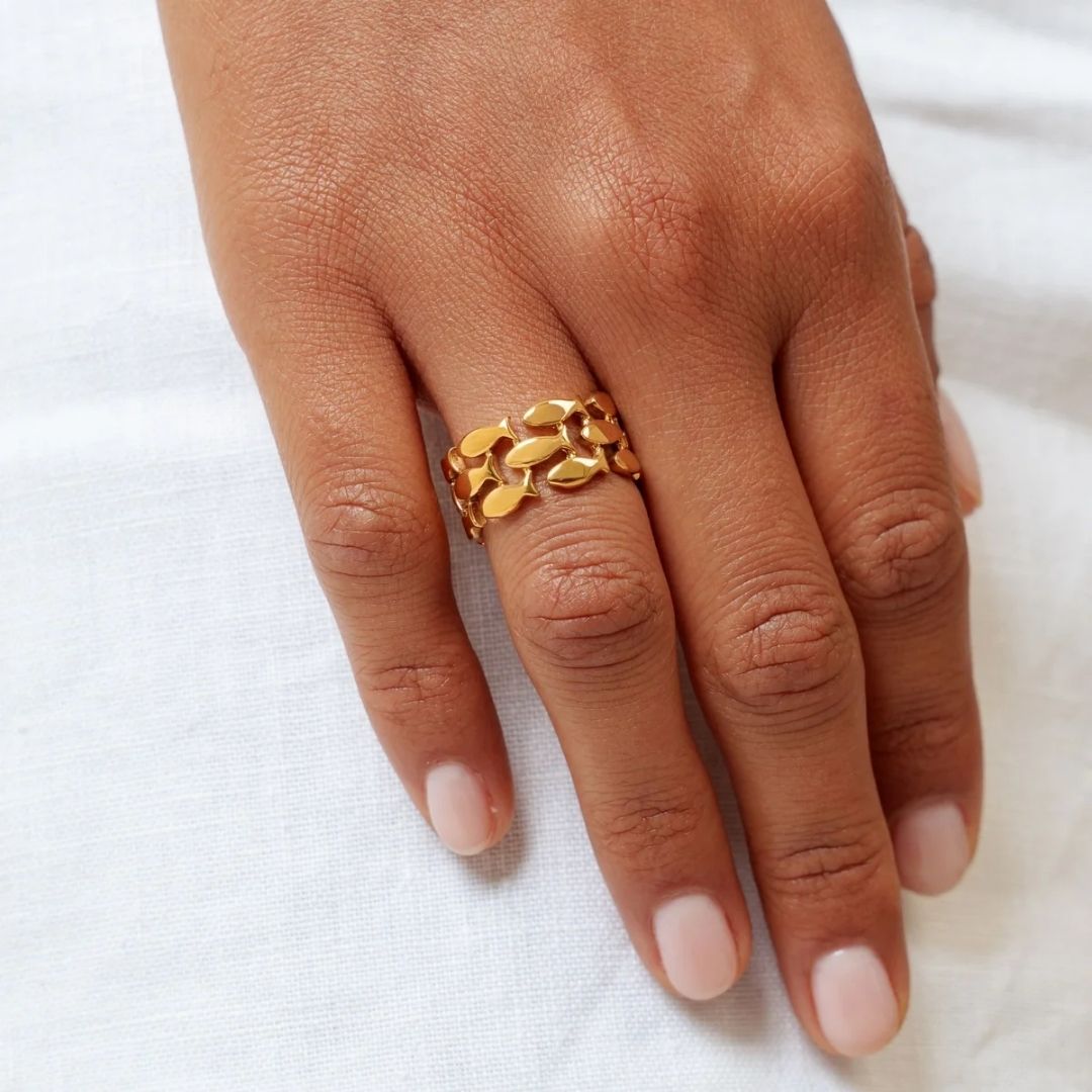 Gold ring on a person's finger against a white background