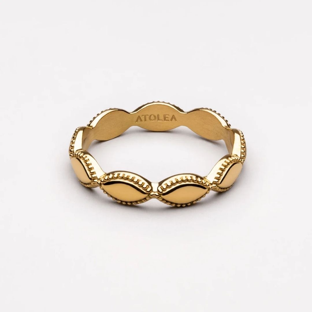 A gold ring with a wavy, scalloped edge and raised oval links separated by beaded borders, shown on a clean white background. The inside of the ring is engraved with the brand name 'ATOLEA'.