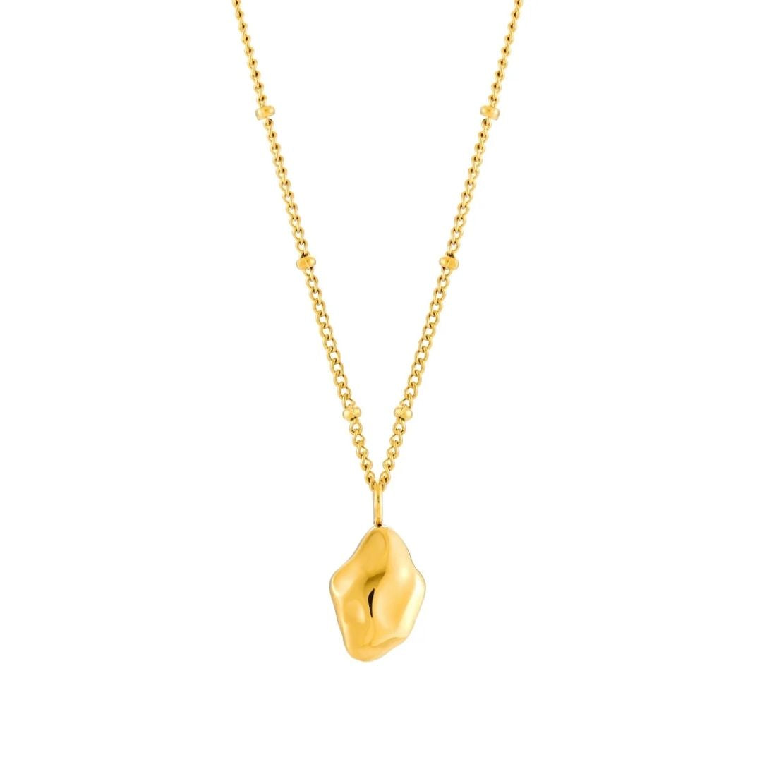 A gold necklace featuring a textured, organic-shaped pendant on a delicate chain with small bead accents, shown against a plain white background.