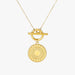 A gold necklace featuring a circular textured pendant with a toggle clasp, shown against a plain light gray background.