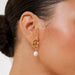 Gold earring with a pearl drop worn by a person