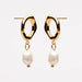A pair of gold dangle earrings with abstract wavy oval hoops and hanging baroque-style white pearls, shown against a plain light gray background.
