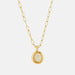 A gold paperclip chain necklace with a round bezel-set opal pendant, shown against a light gray background.