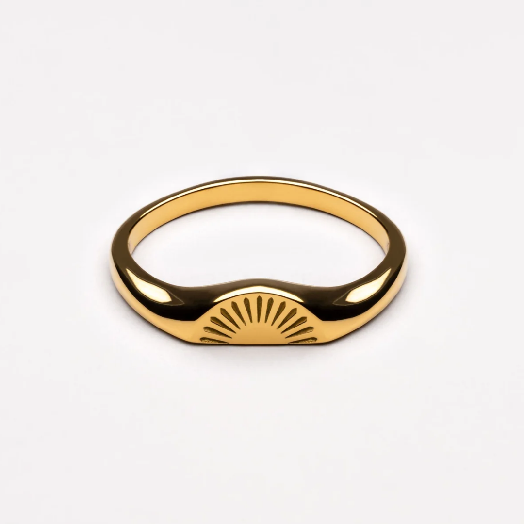 A polished gold signet ring with a sunburst or semi-circle engraved design on the front, displayed on a clean white background.