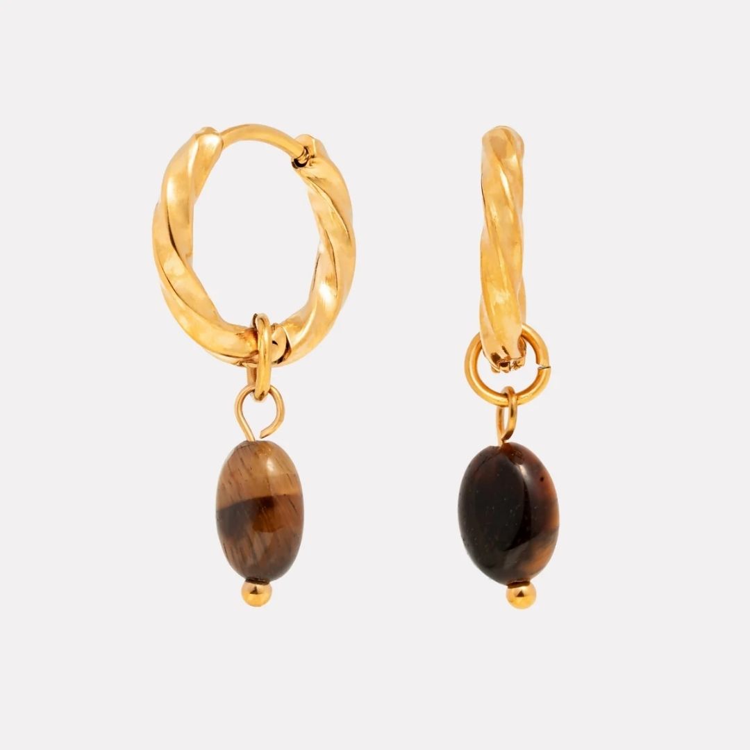 Gold hoop earrings with brown beads on a light gray background