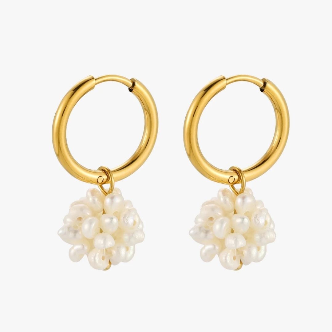 A pair of gold hoop earrings with dangling clusters of irregular white freshwater pearls, shown on a light gray background.