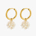 A pair of gold hoop earrings with dangling clusters of irregular white freshwater pearls, shown on a light gray background.