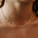 A close-up of a model's neck and collarbone wearing a delicate rose gold chain necklace with small clear beads. The YIMEILI brand logo is visible in the top left corner.