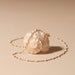A shell-shaped crossbody bag with a cream-colored mother-of-pearl shell body and a delicate gold chain strap, displayed on a warm beige background.