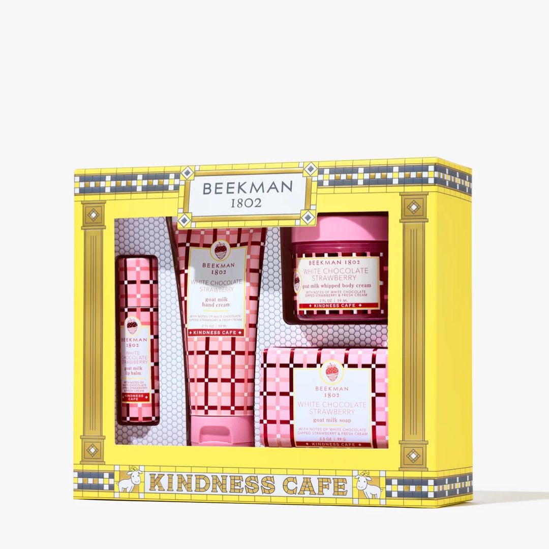 Beeckman 1802 Kindness Cafe gift set containing five pink and white self-care items, including hand cream, body wash, hand cream, body wash, and face cream, presented in a yellow decorative box.