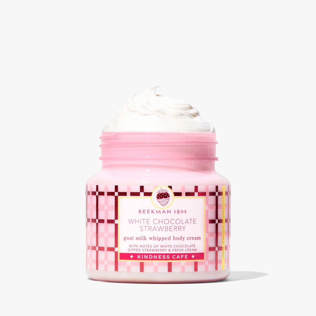 A pink jar of Beekman 1803 White Chocolate Strawberry goat milk whipped body cream, shown open with whipped cream on top against a clean white background.