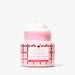 A pink jar of Beekman 1803 White Chocolate Strawberry goat milk whipped body cream, shown open with whipped cream on top against a clean white background.