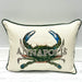 An off-white rectangular throw pillow with dark green piping, featuring a large embroidered blue and green crab and the word 'ANNAPOLIS' across the front.