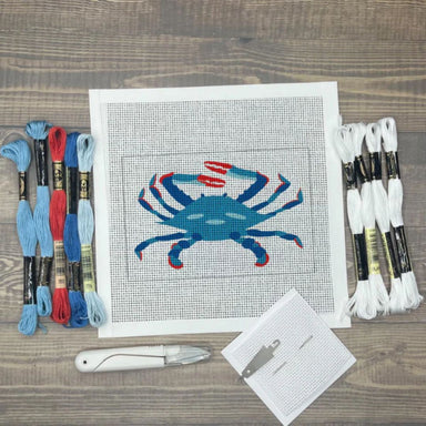 Cross-stitch kit with a blue crab design on a wooden surface