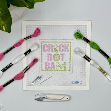 Cross-stitching kit with threads, needle, and scissors on a white surface