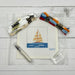 Cross-stitch kit with sailboat design, threads, and tools on a wooden surface