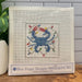 A needlepoint kit in its clear plastic sleeve, featuring a blue crab design with colorful Christmas lights on a white mesh canvas. The packaging label at the bottom reads 'Blue Poppy Designs Needlepoint Kit'.