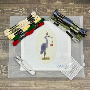 Cross-stitch kit with pre-printed pattern, threads, and tools on a wooden surface