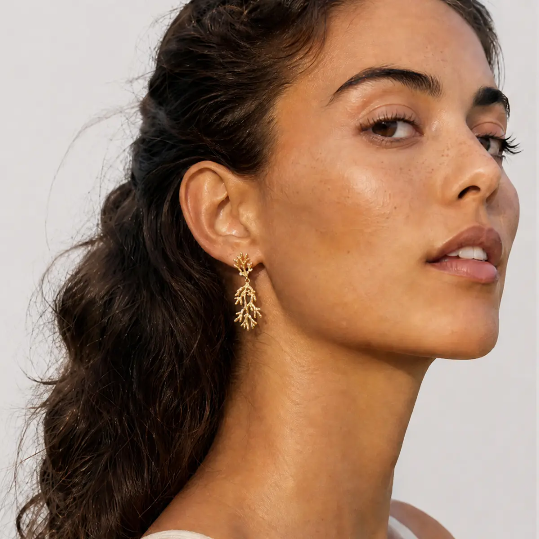 Close-up of a woman wearing gold earrings with a neutral background
