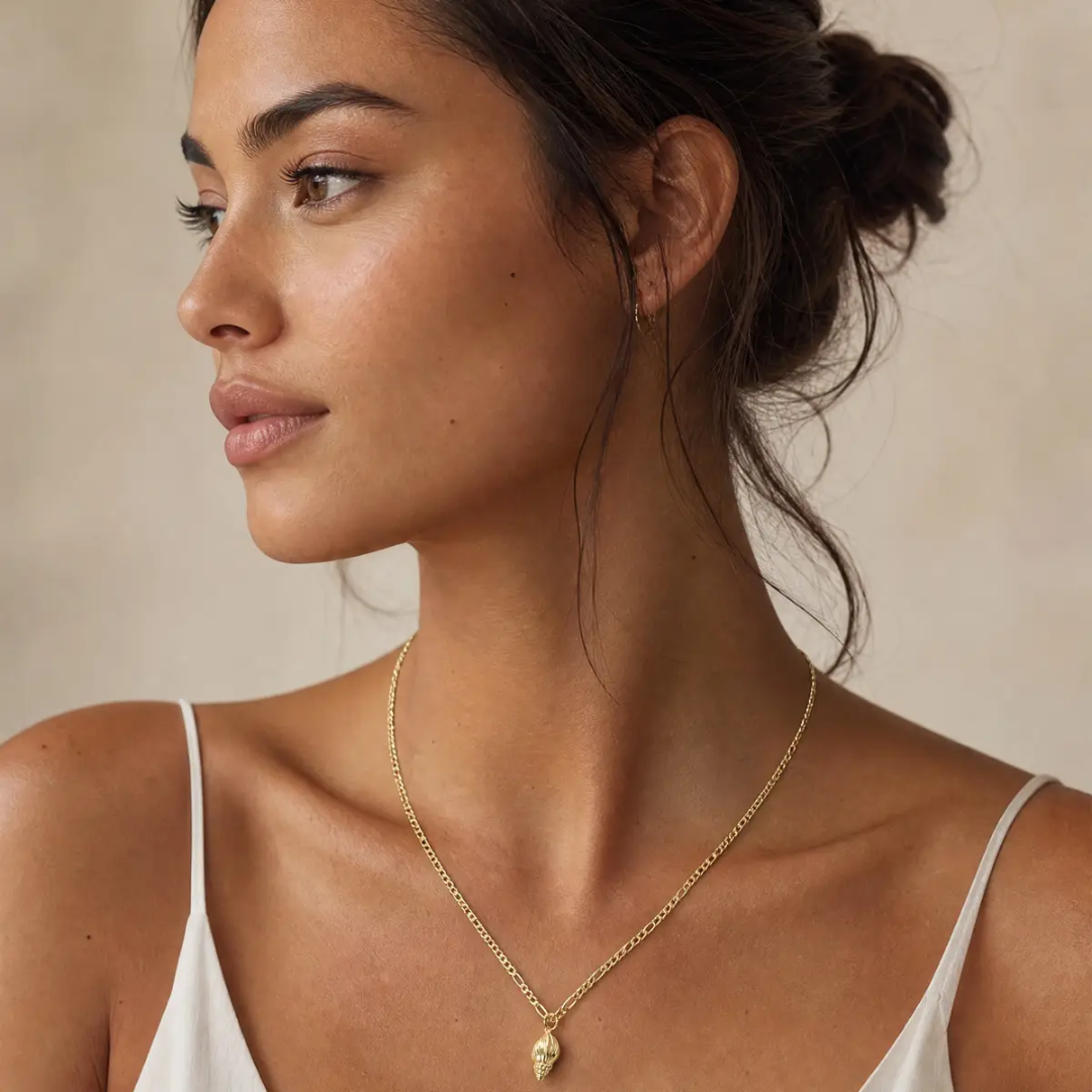 Woman wearing a gold necklace against a neutral background