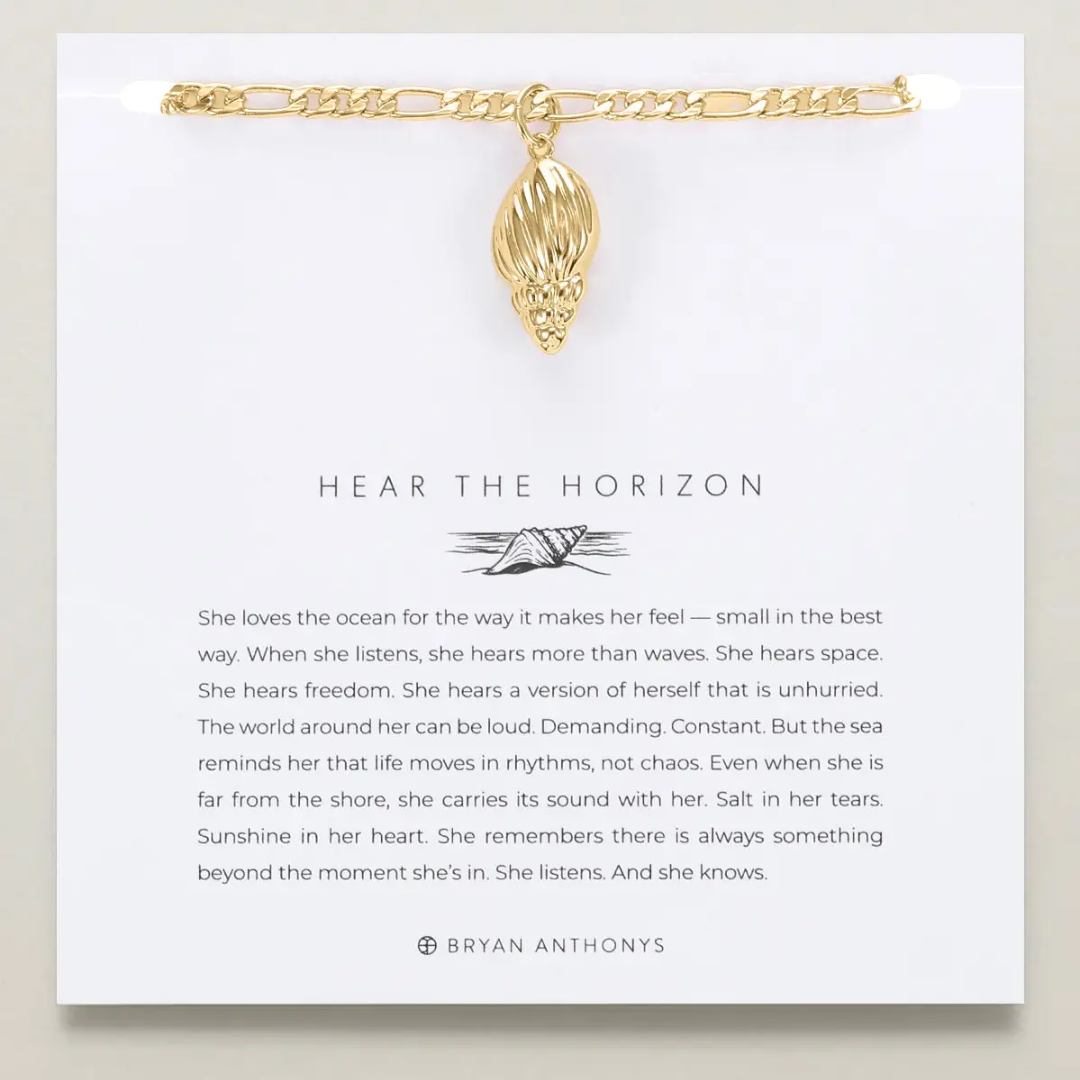 Gold bracelet with a pendant on a card featuring text and branding.