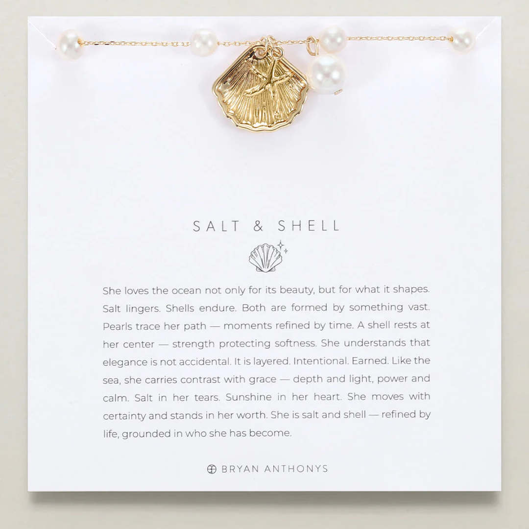 Gold shell necklace on a card with text and branding