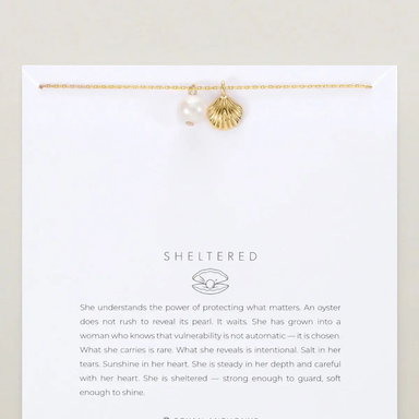 Gold bracelet with pearls on a white card featuring 'Sheltered' brand text.