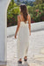 Woman in a white dress standing in a garden with flowers.
