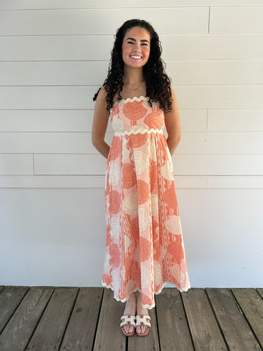 Woman wearing a shell dress standing on a wooden deck with a white wall background