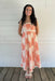 Woman wearing a shell dress standing on a wooden deck with a white wall background