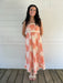 Woman wearing a shell dress standing on a wooden deck with a white wall background