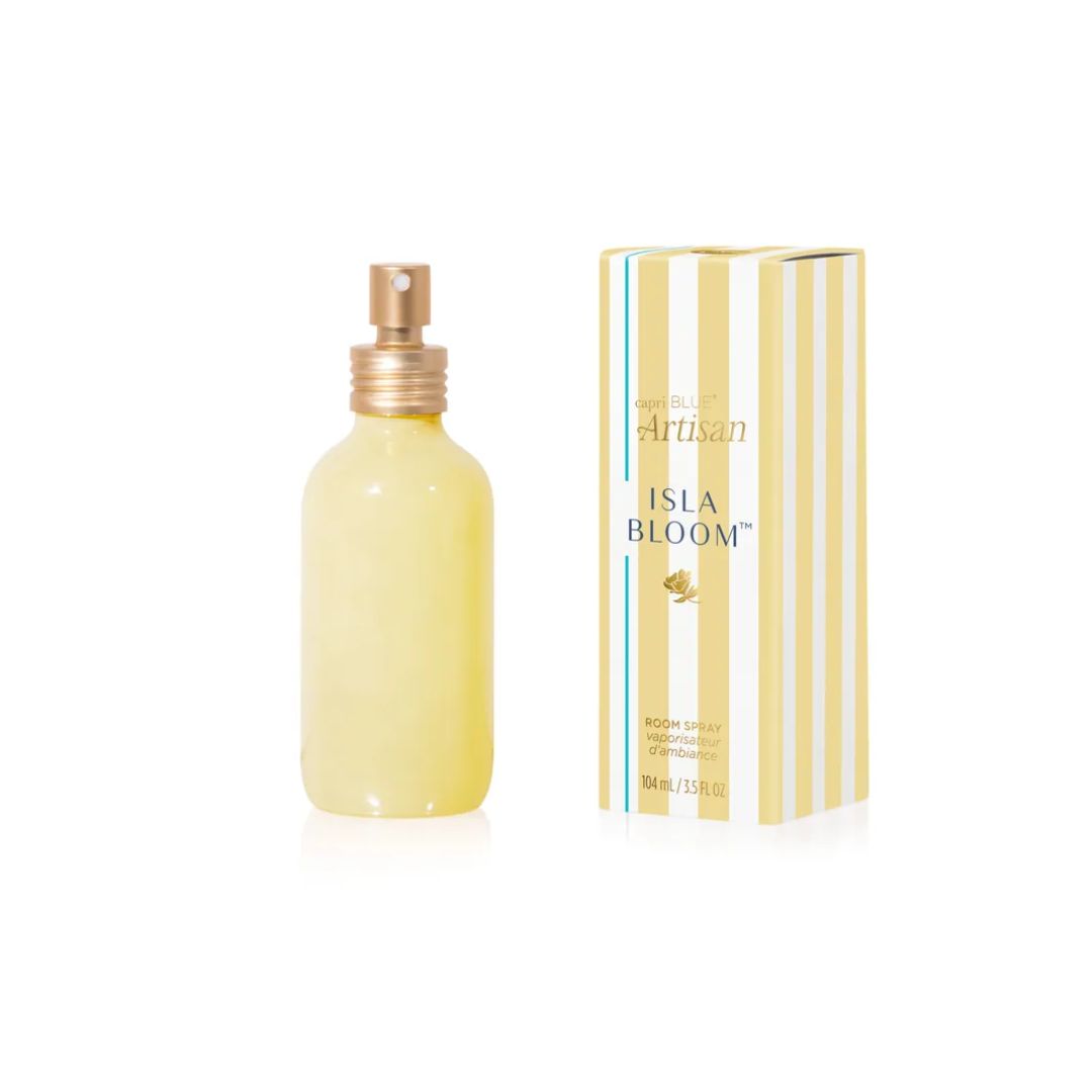 Isla Bloom Artisan cologne bottle and packaging box on a white background. The bottle is a frosted pale yellow glass with a gold spray top, and the box features vertical cream and yellow stripes with blue and gold text.