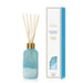 A coconut santal reed diffuser bottle with a light blue glass body, white crystal-like base, and natural wood reeds, shown next to its white and blue packaging box on a white background.