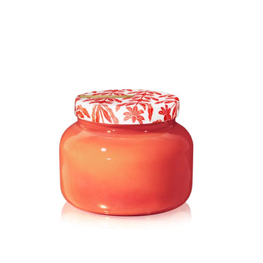 A small glossy jar with a warm coral-orange body and a white lid decorated with a red floral pattern, shown on a clean white background.