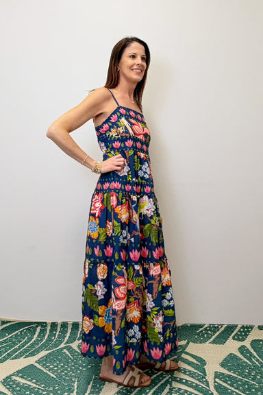 Woman wearing a floral dress standing against a plain wall.