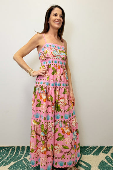 Woman wearing a colorful floral dress against a plain background