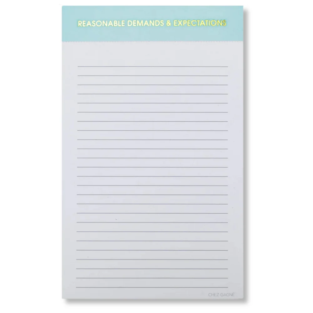 A lined notepad with a light blue header band at the top that reads 'REASONABLE DEMANDS & EXPECTATIONS' in yellow text. The notepad has thin horizontal gray lines across a white page and is photographed on a light gray background.