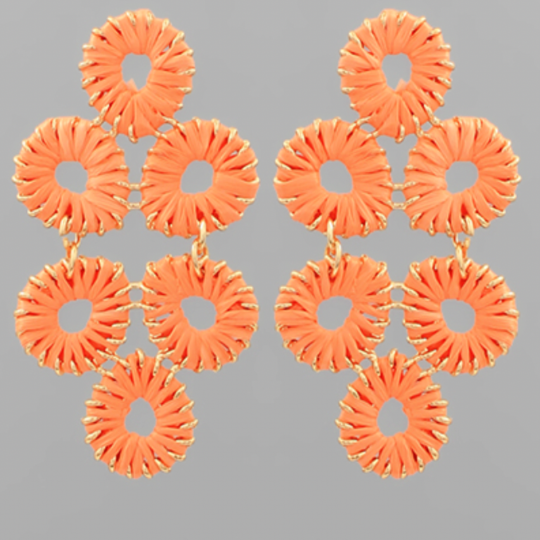 Pair of orange earrings with circular design on a gray background