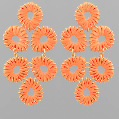Pair of orange earrings with circular design on a gray background